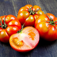Almanac Planting Co: Beefsteak Tomato sliced open showing meaty red interior and juicy texture on a rustic wooden surface