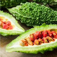 Almanac Planting Co: Sliced Ganjyu Bitter Melon showing bright green rind and red-orange seed interior on a cutting board