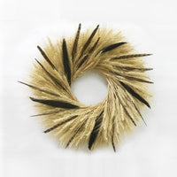 A hand made wreath made out of blonde wheat, majesty millet, and pheasant feathers.