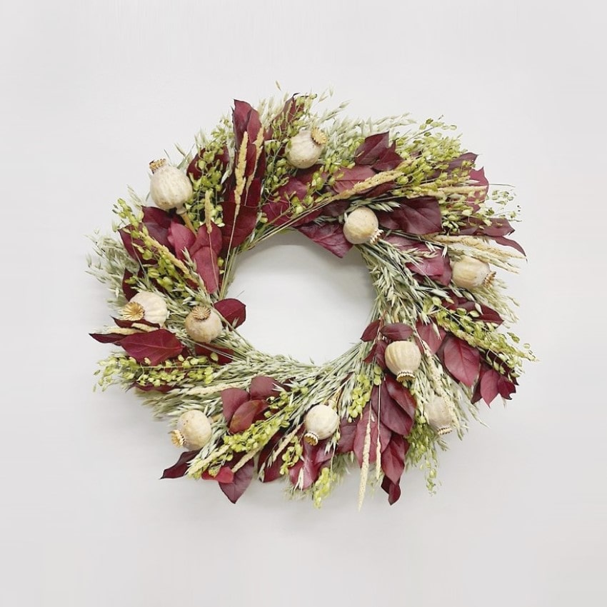 A hand made to order fresh wreath of avena oats, preserved burgundy salal, lupidium field pennycress, feather reed grass, poppy pods.