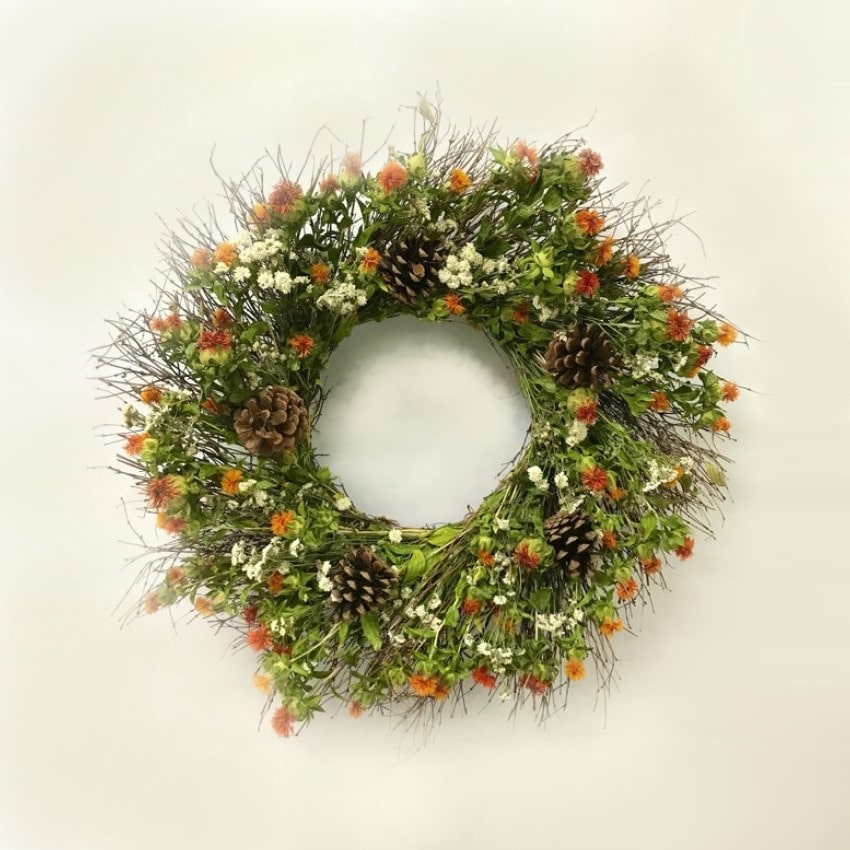 A handmade fresh wreath with quail brush eggs, safflower, pearly everlasting, and austriaca pine cones.